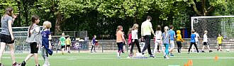 Ferientagescamp Kinder auf Sportplatz mit Betreuuer