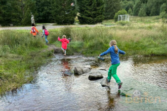 bei einem survivalprogramm lernen kinder ueber steine zu springen, feuer selbst zu machen und einen unterschlupf zu bauen