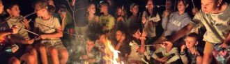 ein gemeinsames lagerfeuer bringt gruppen auus kindern bei feriencamps zusammen
