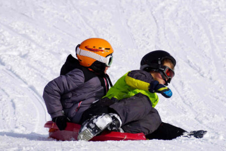 Kinder fahren Schlitten beim Feriencamp im Winter