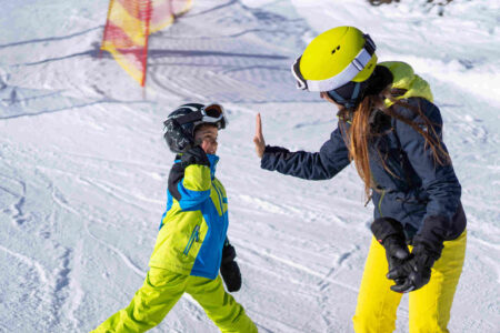 Anfaengerkurs-ski-fahren-junge-gibt-five-mit-trainerin