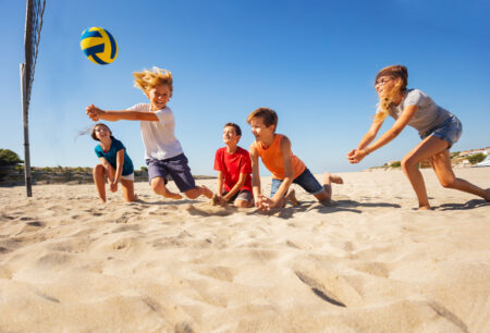 fuenf-kinder-spielen-volleyball-im-sand