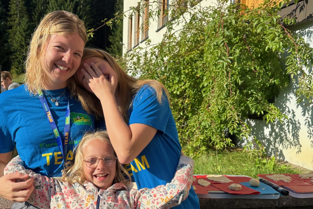 2-teamerinnen-lachen-mit-maedchen-bei-camp